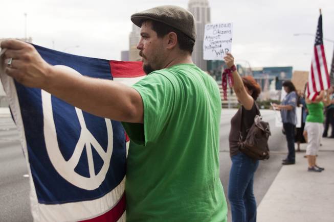 A man holds up a peace flag during a protest against U.S. intervention in Syria held on Tropicana and the I-15, Saturday, Aug. 31, 2013.