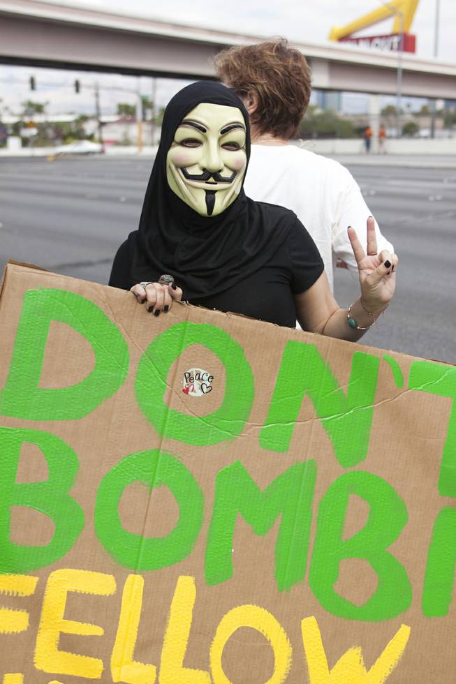 A masked protester holds up a peace sign during a protest against U.S. intervention in Syria held on Tropicana and the I-15, Saturday, Aug. 31, 2013.