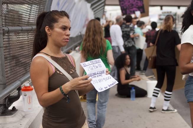 Marybel Gomez holds up a sign with President Obama and Secretary of State John Kerry's phone numbers during a protest against U.S. intervention in Syria held on Tropicana and the I-15, Saturday, Aug. 31, 2013.