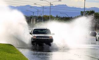 A car drives through a flooded area on Sunset Road on Monday, September 2, 2013. The National Weather Service issued a flash flood warning for areas of Henderson late in the afternoon.