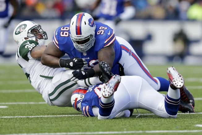 New York Jets fullback Lex Hilliard (36) is tackled by Buffalo Bills defensive tackle Marcell Dareus (99) and linebacker Bryan Scott (43) during the first half of an NFL football game on Sunday, Dec. 30, 2012, in Orchard Park, N.Y. 
