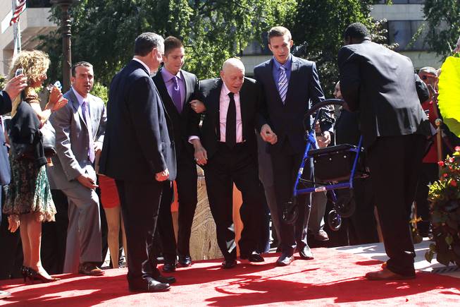 Former UNLV coach Jerry Tarkanian refuses his walker as he makes his way, aided by grandsons Jerry and John King, down the red carpet and up the stairs to Symphony Hall for his induction into the Naismith Memorial Basketball Hall of Fame Sunday, Sept. 8, 2013 in Springfield, Mass.