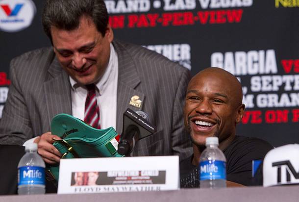 Floyd Mayweather Jr., right, smiles after looking over a WBC super welterweight belt during a news conference at the MGM Grand Wednesday, Sept. 11, 2013. Mauricio Sulaiman, WBC executive director, is at left. Mayweather and Canelo Alvarez of Mexico will meet for a WBC/WBA 154-pound title fight at the MGM Grand Garden Arena on Saturday.