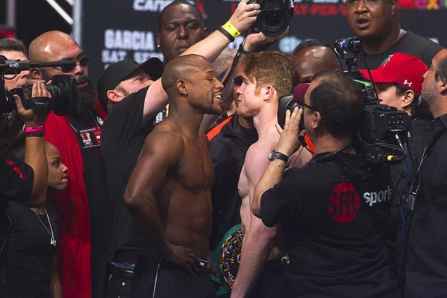 Undefeated boxers Floyd Mayweather Jr., left, and Canelo Alvarez of Mexico face off during an official weigh-in at the MGM Grand Garden Arena Friday Sept. 13, 2013. The boxers will face each other in a WBC/WBA 154-pound title fight at the arena Saturday.