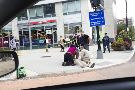 People attend to a man lying on the ground at the corner of New Jersey and M streets, a block away from the Washington Navy Yard shooting, Monday, Sept. 16, 2013. It is the only known photo of one of the victims in the tragedy. 