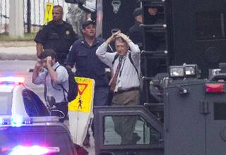 People hold their hands to their heads as they are escorted out of the building where a deadly shooting rampage occurred at the Washington Navy Yard in Washington, Monday, Sept. 16, 2013. One shooter was killed, but police said they were looking for two other possible gunmen wearing military-style uniforms.