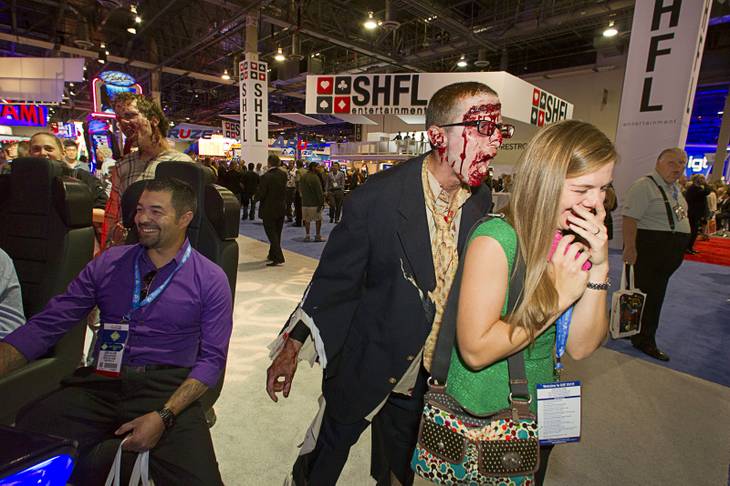 A zombie goes after Marie Kay Williams by a display of Aristocrat's "Walking Dead" video slot machines during the G2E convention at the Sands Expo Center Tuesday, Sept. 24, 2013. The slots are themed after AMC's Walking Dead television drama.