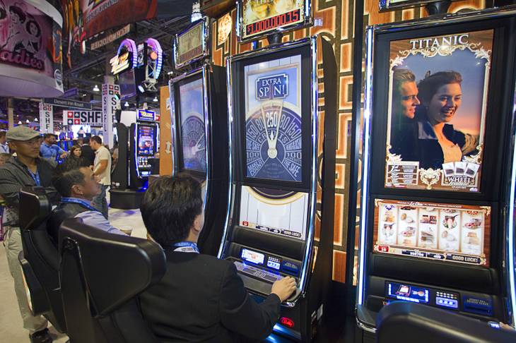 People try out new Titanic slot machines by Bally Technologies during the G2E convention at the Sands Expo Center Tuesday, Sept. 24, 2013.  The slots are themed after the 1997 "Titanic" movie starring Leonardo DiCaprio and Kate Winslet.