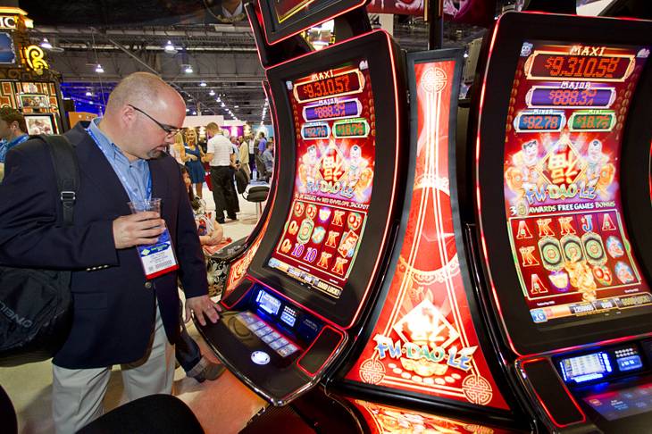 Jose Figueroa of Puerto Rico looks over slot machines in Bally Technologies' Pro Wave cabinets during the G2E convention at the Sands Expo Center Tuesday, Sept. 24, 2013.