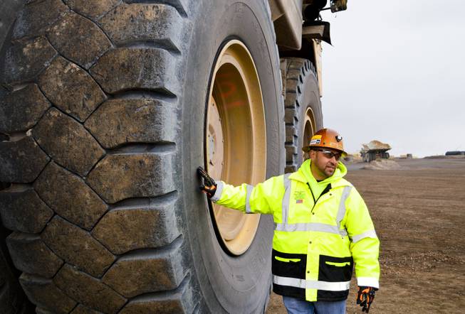 Benjie Gallegos of Newmont Mining Corp. stands next to a Caterpillar dump truck with tires that are more than 13 feet tall. The photo was taken at the Carlin mine complex west of Elko on Sept. 26, 2013.