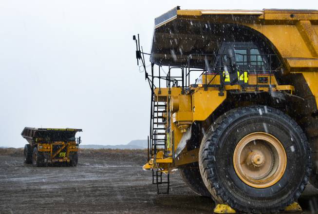Two massive Caterpillar dump trucks with tires that are more than 13 feet tall stand in the snow at the Carlin mine complex west of Elko on Sept. 26, 2013.
