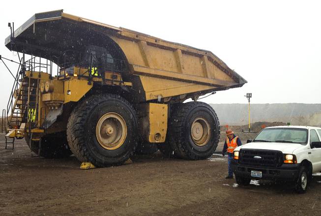 A Caterpillar dump truck dwarfs the man and work truck next to it on Sept. 26, 2013, at Newmont Mining Corp.'s Carlin complex west of Elko.