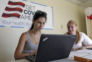 Ashley Hentze, left, of Lakeland, Fla., gets help signing up for the Affordable Care Act from Kristen Nash, a volunteer with Enroll America, a private, nonprofit organization running a grassroots campaign to encourage people to sign up for health care, Tuesday, Oct. 1, 2013  