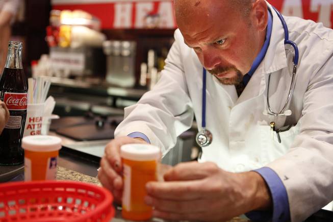 Manager Andrew Stewart prepares alcohol shots in prescription canisters at the Heart Attack Grill in downtown Las Vegas on Tuesday, October 8, 2013.