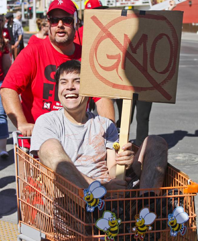 Dale Andriaansen pushes Andrew Russell in a shopping cart during the "March Against Monsanto" protest opposing genetically modified food in downtown Las Vegas, Saturday, Oct. 12, 2013.
