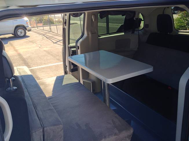 The interior of the van has a kitchen table with bench seats that convert into a double bed.