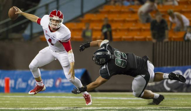 Fresno State quarterback Derek Carr, left, escapes from Hawaii defensive lineman Beau Yap in the fourth quarter on Saturday, Sept. 28, 2013, in Honolulu. Fresno State held off Hawaii 42-37. 