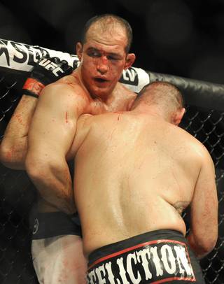A bloodied Junior Dos Santos, left, looks to his coaches during a UFC World Heavyweight title fight with UFC heavyweight champion Cain Velasquez in Houston, Saturday, Oct. 19, 2013. Velasquez kept his title, beating Santos with a TKO in the fifth round. (AP Photo/Pat Sullivan)