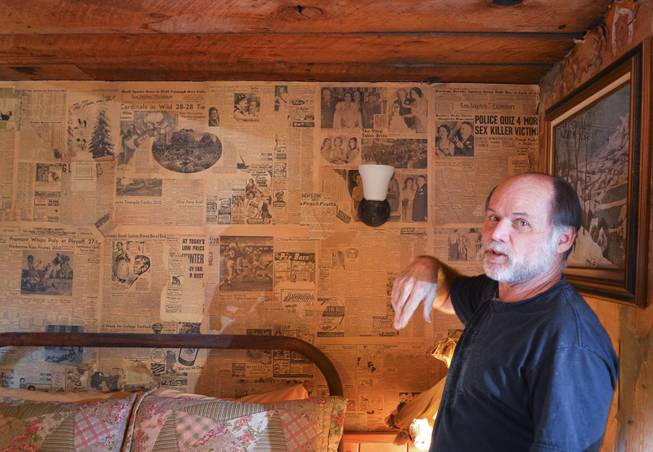 Herb Robbins, who has spent the last 35 years restoring Gold Point, points to a newspaper inside a restored miners cabin, Tuesday, Oct. 22, 2013. Robins takes old newspaper, some of which was used as insulation inside the cabin walls, to make wallpaper. (Note the headline on the old Los Angeles Examiner in the upper right corner. It says police "quiz" victims of a killer, which Robbins points out, should be impossible.)