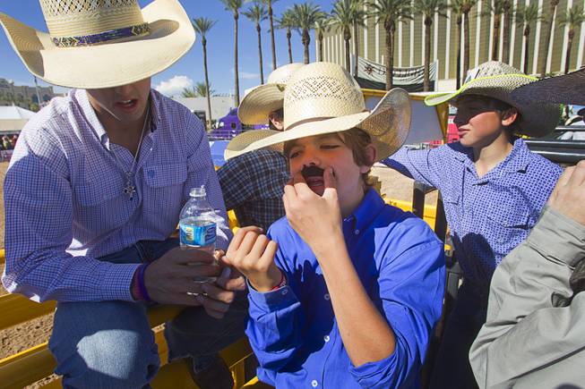 Dawson Gleaves, 12, of Amarillo, Texas applies a fake mustache before competing in the third go round of the Chris Shivers Miniature Bull Riding (MBR) World Finals at Mandalay Bay Thursday, Oct. 24, 2013. The MBR features junior riders ages 8 to11 and senior riders ages 12 to 14. The event was part of the the 2013 Professional Bull Riders Built Ford Tough World Finals.