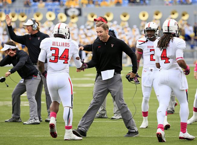 Texas Tech coach Kliff Kingsbury celebrates with Kenny Williams (34) following a touchdown run in the fourth quarter of their NCAA college football game against West Virginia in Morgantown, W.Va., on Saturday, Oct. 19, 2013. Texas Tech won 37-27. 