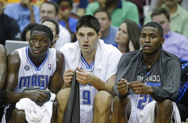 Orlando Magic players, from left, Victor Oladipo, Nikola Vucevic (9), and Maurice Harkless watch action on the court against the New Orleans Pelicans during the second half of an NBA preseason basketball game in Jacksonville, Fla., Wednesday, Oct. 9, 2013. New Orleans won the game 99-95.