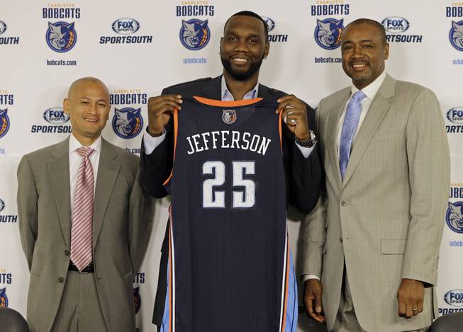 Charlotte Bobcats' Al Jefferson, center, holds up his jersey with Rod Higgins, right, president of basketball operations, and Rich Cho, left, general manager, during a news conference for the NBA basketball team in Charlotte, N.C., Wednesday, July 10, 2013. Jefferson, a free agent, signed with the Bobcats today. 