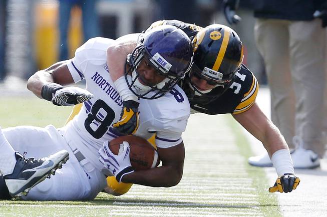 Northwestern Wildcats running back Stephen Buckley (8) is wrapped up by Iowa Hawkeyes defensive back John Lowdermilk (37) during the second half of an NCAA college football game Saturday, Oct. 26, 2013 at Kinnick Stadium in Iowa City, Iowa.