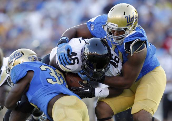 Colorado running back Christian Powell, center, is stopped by UCLA linebacker Myles Jack, left, and UCLA defensive end Keenan Graham, right, for no gain in the first half of their NCAA college football game Saturday, Nov. 2, 2013, in Pasadena, Calif. 
