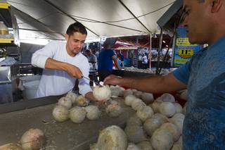 Daniel Muniz, left, prepares a coconut for a customer in the Arreolas Produce stand at the Broadacres Marketplace & Events Center Sunday Nov. 3, 2013.