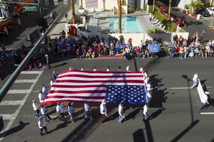 A Cox Communications entry carries an American flag during the annual Veterans Day parade in downtown Las Vegas Monday, Nov. 11, 2013.