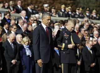 President Barack Obama and Maj. Gen. Jeffrey S. Buchanan of the U.S. Army Military District of Washington, left, lower their heads after the president placed a wreath at the Tomb of the Unknowns at Arlington National Cemetery in Arlington, Va., Monday, Nov. 11, 2013, during a Veterans Day ceremony. Vice President Joe Biden and his wife Jill are at left.