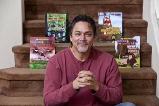 Brian Fujikawa poses with four currently published books he coauthored with his daughter Daisy Thursday, Nov. 13, 2013. 