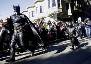 Miles Scott, dressed as Batkid, right, runs with Batman after saving a damsel in distress in San Francisco, Friday, Nov. 15, 2013. 