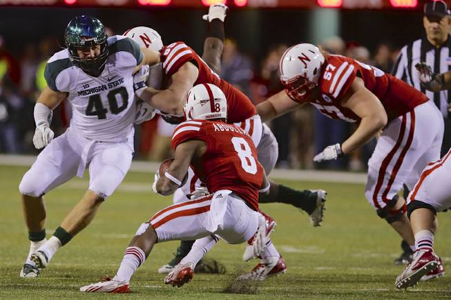 Nebraska running back Ameer Abdullah (8) tries to veer away from Michigan State linebacker Max Bullough (40) in the second half of an NCAA college football game in Lincoln, Neb., Saturday, Nov. 16, 2013. 