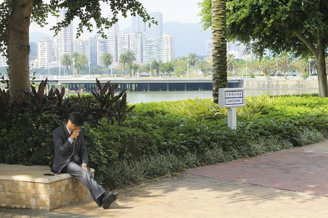 A man talks into a mobile phone with the Pearl River in the background in downtown Macau.