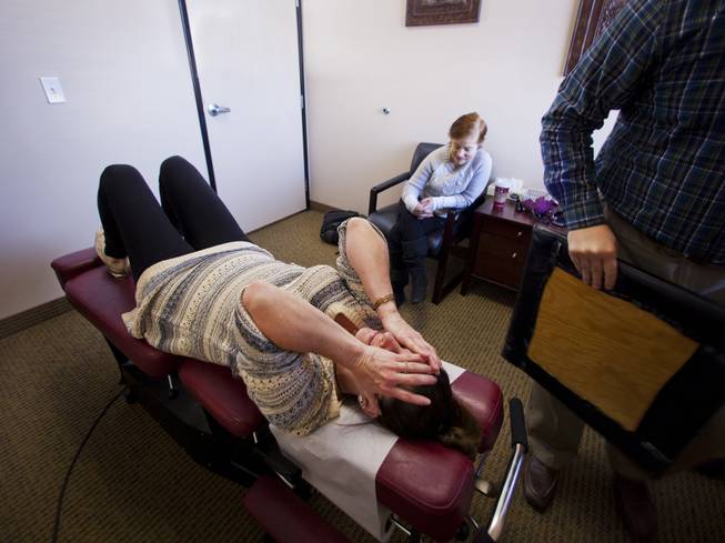 Karen Stiles reacts after being adjusted by chiropractor Dr. Scott Wallace as her daughter Jenny laughs at the usual scream from her mother following each adjustment session Wednesday, Nov. 20, 2013.