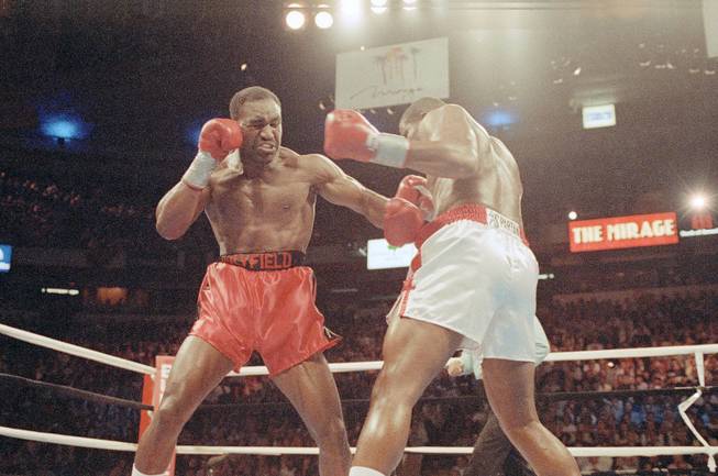 Evander Holyfield, left, lands a punch to body of challenger Riddick Bowe in the first round of heavyweight title fight on Friday, Nov. 13, 1992 in Las Vegas. 