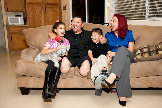 Eddie Garcia, whose positive attitude is remarkable, laughs with his his wife, Antoinette, daughter, Haley, 11, and son Ryan, 7 while posing for a family portrait in their Henderson home Wednesday evening, Nov. 11, 2013.  Eddie lost his arms and legs due to complication from a skin-eating bacterial infection in January 2013.