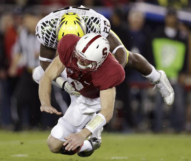 Oregon linebacker Derrick Malone (22) tackles Stanford quarterback Kevin Hogan after Hogan passed the ball during the first quarter of an NCAA college football game in Stanford, Calif., Thursday, Nov. 7, 2013.