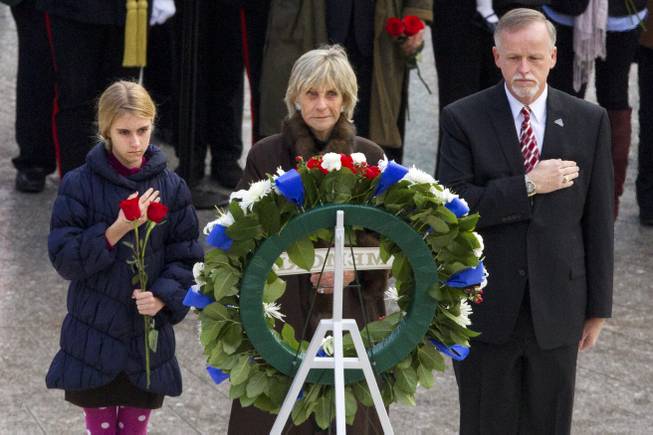 An unidentified girl, left, holds a rose during a wreath laying ceremony with former Ambassador to Ireland Jean Kennedy Smith, center, and Patrick Hallinan, executive director of Army National Military Cemeteries, at the grave of John F. Kennedy at Arlington National Cemetery, in Arlington, Va., Friday, Nov. 22, 2013, on the 50th anniversary of Kennedy's death.