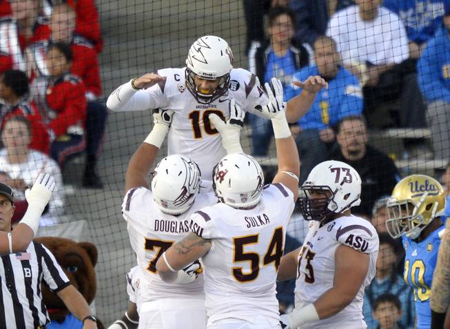 Arizona State quarterback Taylor Kelly celebrates his touchdown with offensive linesmen Jamil Douglas, Tyler Sulka and Vi Teofilo as UCLA cornerback Fabian Moreau watches during the first half of an NCAA football game Saturday, Nov. 23, 2013, in Pasadena, Calif. 