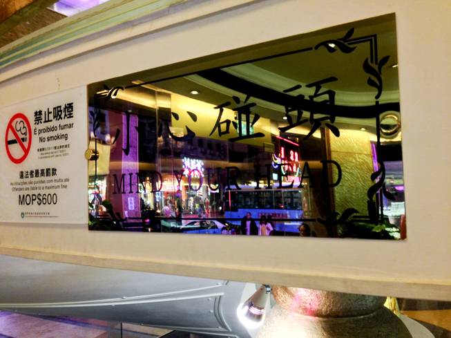 A window with the words "Mind Your Head" written on it in downtown Macau.