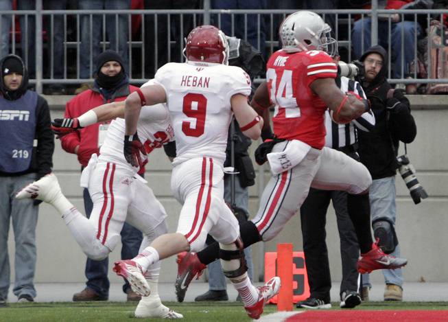 Ohio State running back Carlos Hyde, right, scores against Indiana's Mark Murphy, left, and Greg Heban during the first quarter of an NCAA college football game Saturday, Nov. 23, 2013, in Columbus, Ohio. 