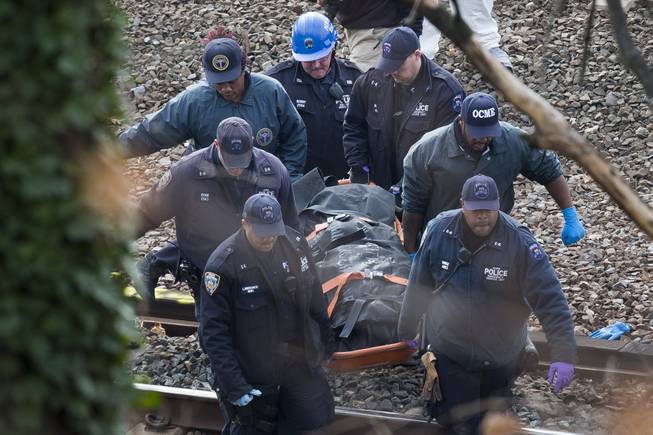 Emergency personnel remove a body from the scene of a Metro-North passenger train derailment in the Bronx borough of New York, Sunday, Dec. 1, 2013. The train derailed on a curved section of track in the Bronx on Sunday morning, coming to rest just inches from the water, killing at least four people and injuring more than 60, authorities said. Metropolitan Transportation Authority police say the train derailed near the Spuyten Duyvil station.