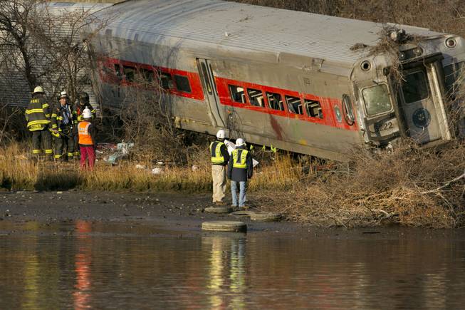 Officials with the National Transportation Safety Board inspect a derailed Metro North commuter train where it almost fell into the Harlem River, Sunday, Dec. 1, 2013 in the Bronx borough of New York. The Metro-North train derailed on a curved section of track early Sunday, coming to rest just inches from the water, killing at least four people and injuring more than 60, authorities said.