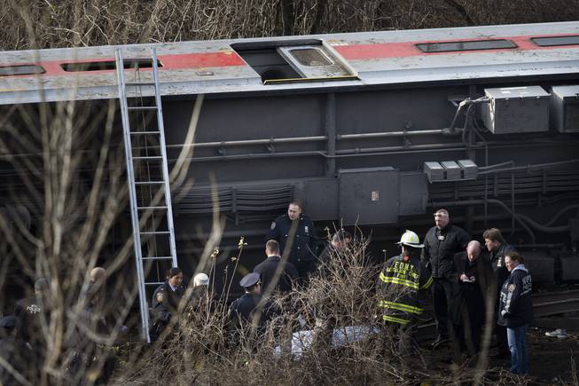 Emergency personnel respond to the scene of a Metro-North passenger train derailment in the Bronx borough of New York, Sunday, Dec. 1, 2013. The train derailed on a curved section of track in the Bronx on Sunday morning, coming to rest just inches from the water, killing at least four people and injuring more than 60, authorities said. Metropolitan Transportation Authority police say the train derailed near the Spuyten Duyvil station.