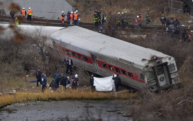 Viewed from Manhattan, first responders and others work at the scene of a  derailed Metro North passenger train in the Bronx borough of New York Dec. 1, 2013. The train derailed on a curved section of track in the Bronx early Sunday, coming to rest just inches from the water, killing at least four people and injuring more than 60, authorities said. Police divers searched the waters to make sure no passenger had been thrown in, as other emergency crews scoured the surrounding woods.