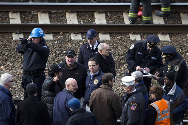 New York Governor Andrew Coumo, center, NYPD Police Commissioner Ray Kelly, center right, and MTA Chairman and CEO Thomas Prendergast, center left, stand by the tracks at the scene of a Metro-North passenger train derailment in the Bronx borough of New York, Sunday, Dec. 1, 2013. The train derailed on a curved section of track in the Bronx on Sunday morning, coming to rest just inches from the water and causing multiple fatalities and dozens of injuries, authorities said.