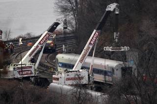 Cranes lift a derailed Metro-North train car, Monday, Dec. 2, 2013, in the Bronx borough of New York. Federal authorities began righting the cars Monday morning as they started an exhaustive investigation into what caused a New York City commuter train rounding a riverside curve to derail, killing four people and injuring more than 60 others. A second 